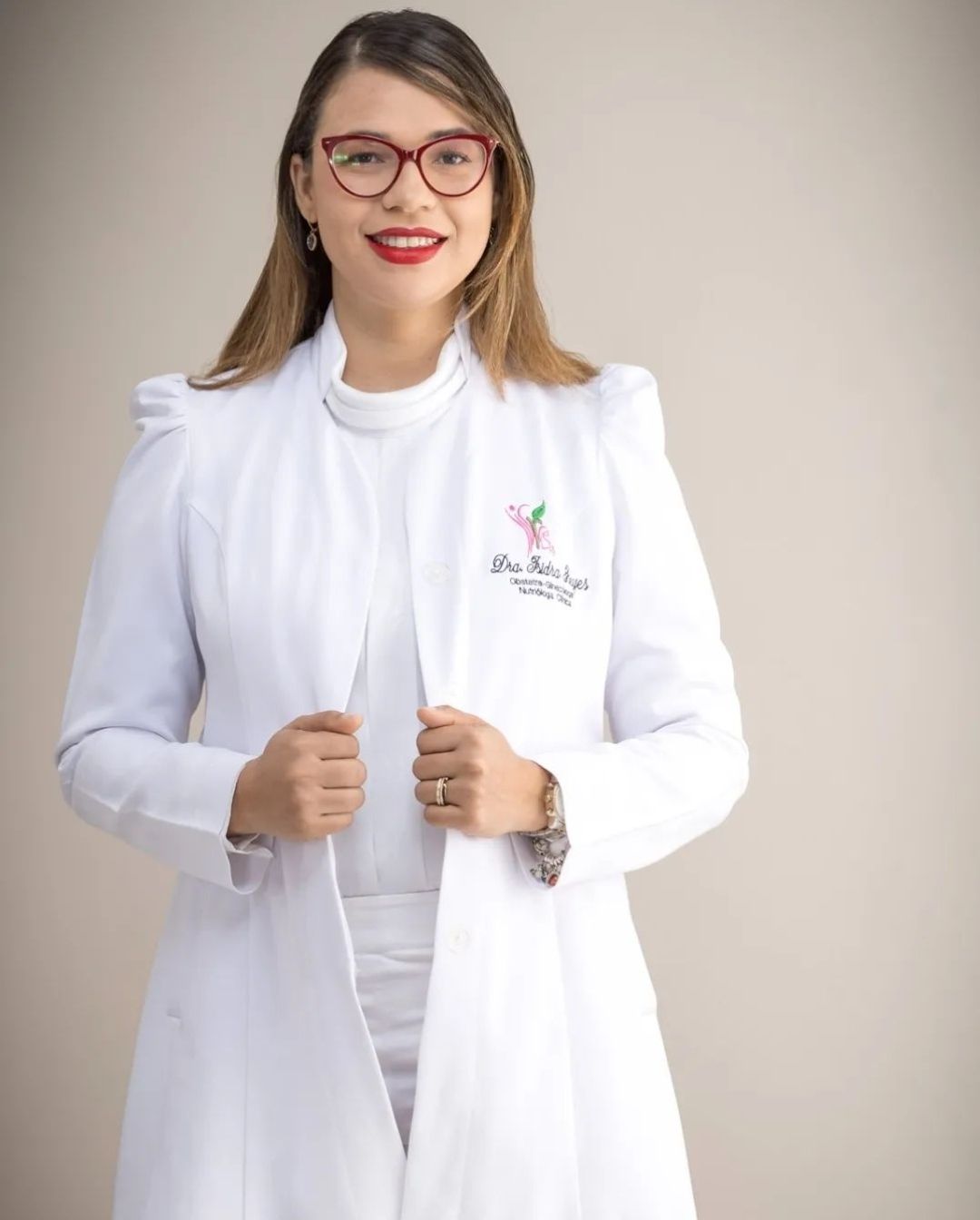 La Dra. Isidra Reyes con bata blanca bordada con su logo, sonriendo